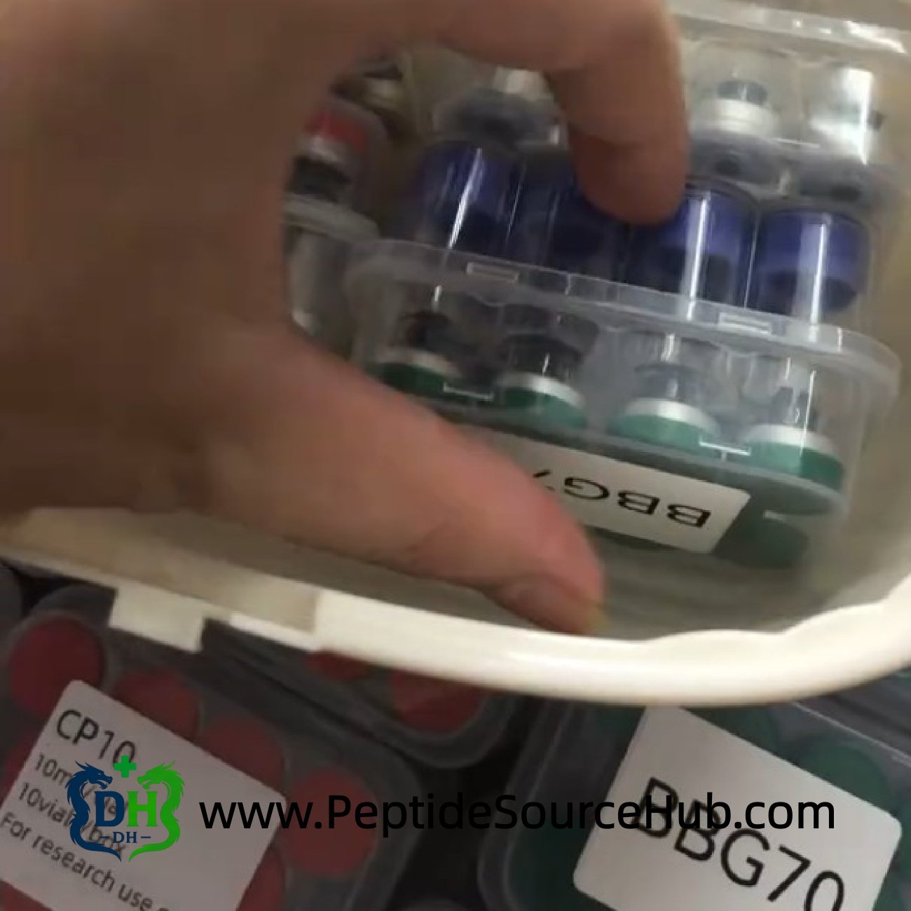 Hand picking up BBG70 Glow peptide tray from container