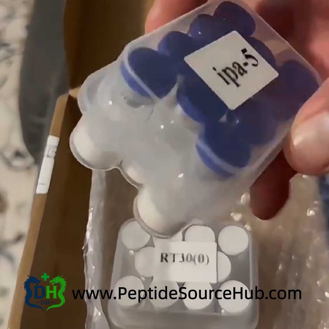 Hand holding Ipamorelin Ipa5 tray over mixed peptide stock