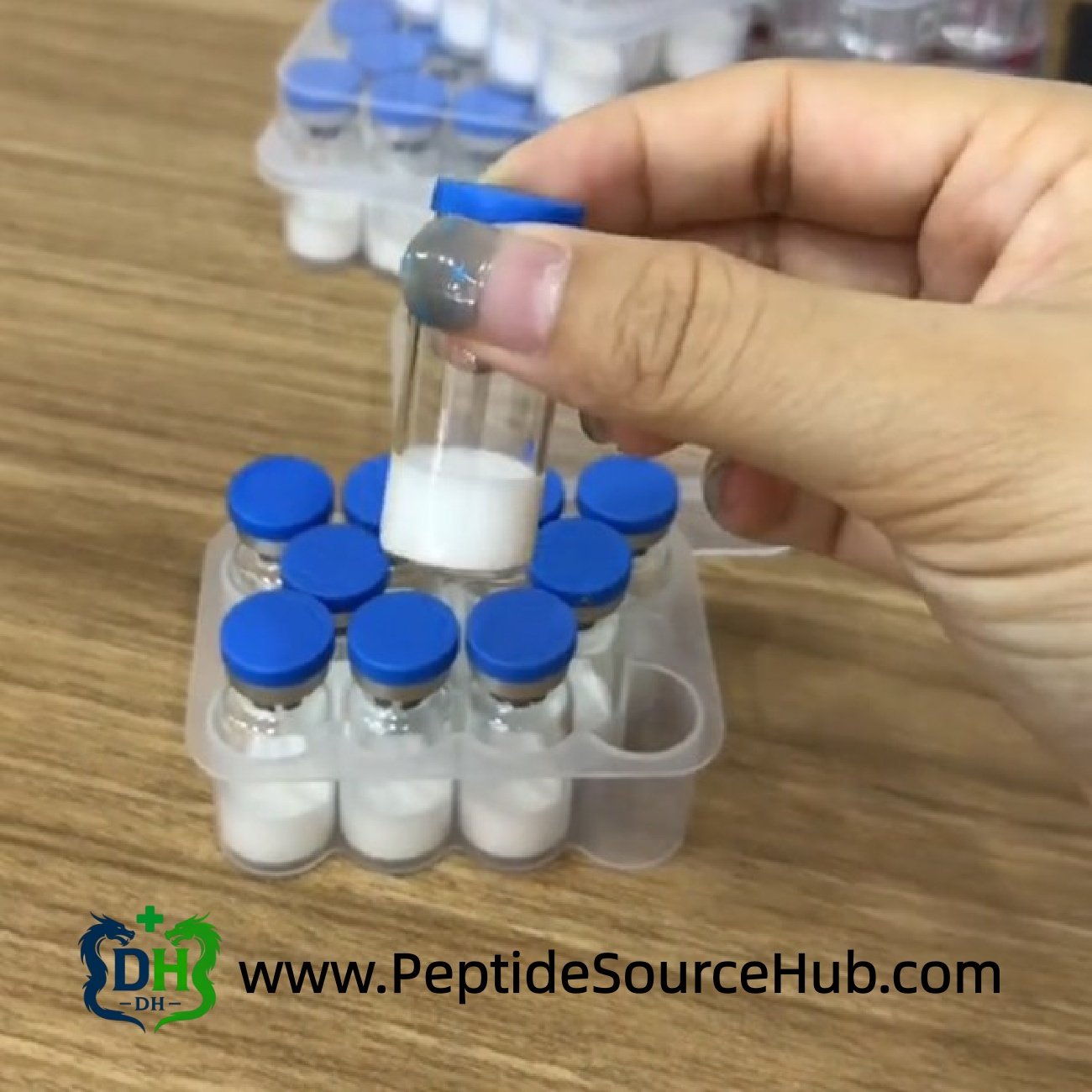 Hand lifting peptide vial from tray on wooden table