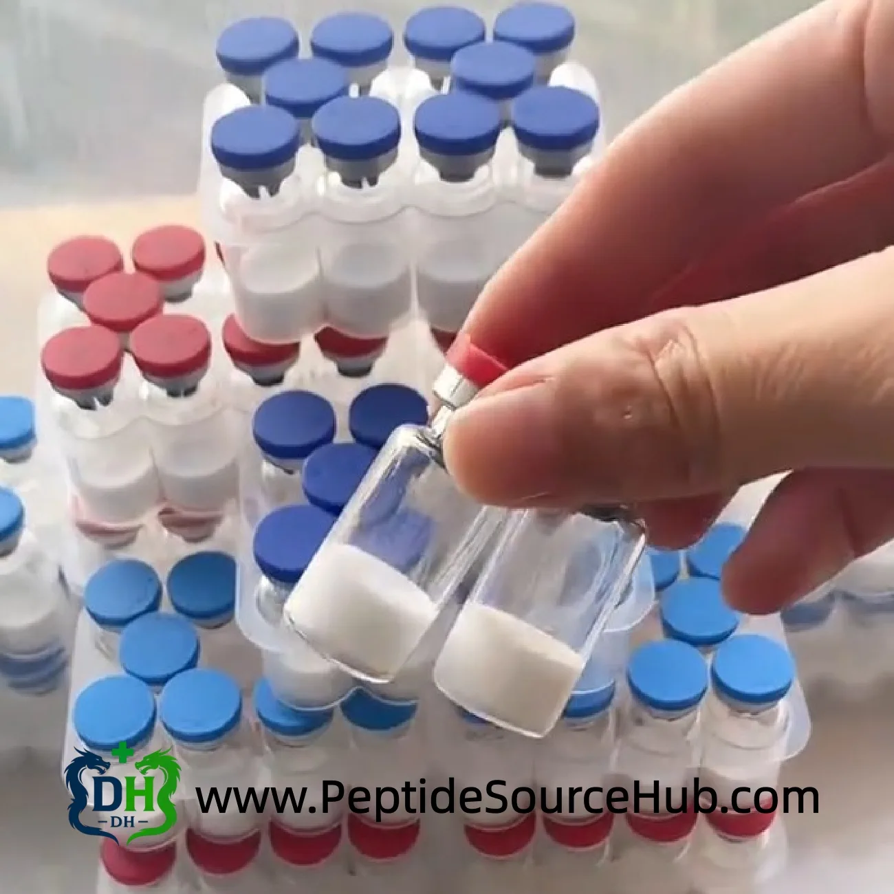 Eine Hand hält zwei Peptide vials vor gestapelten blauen und roten Kits
