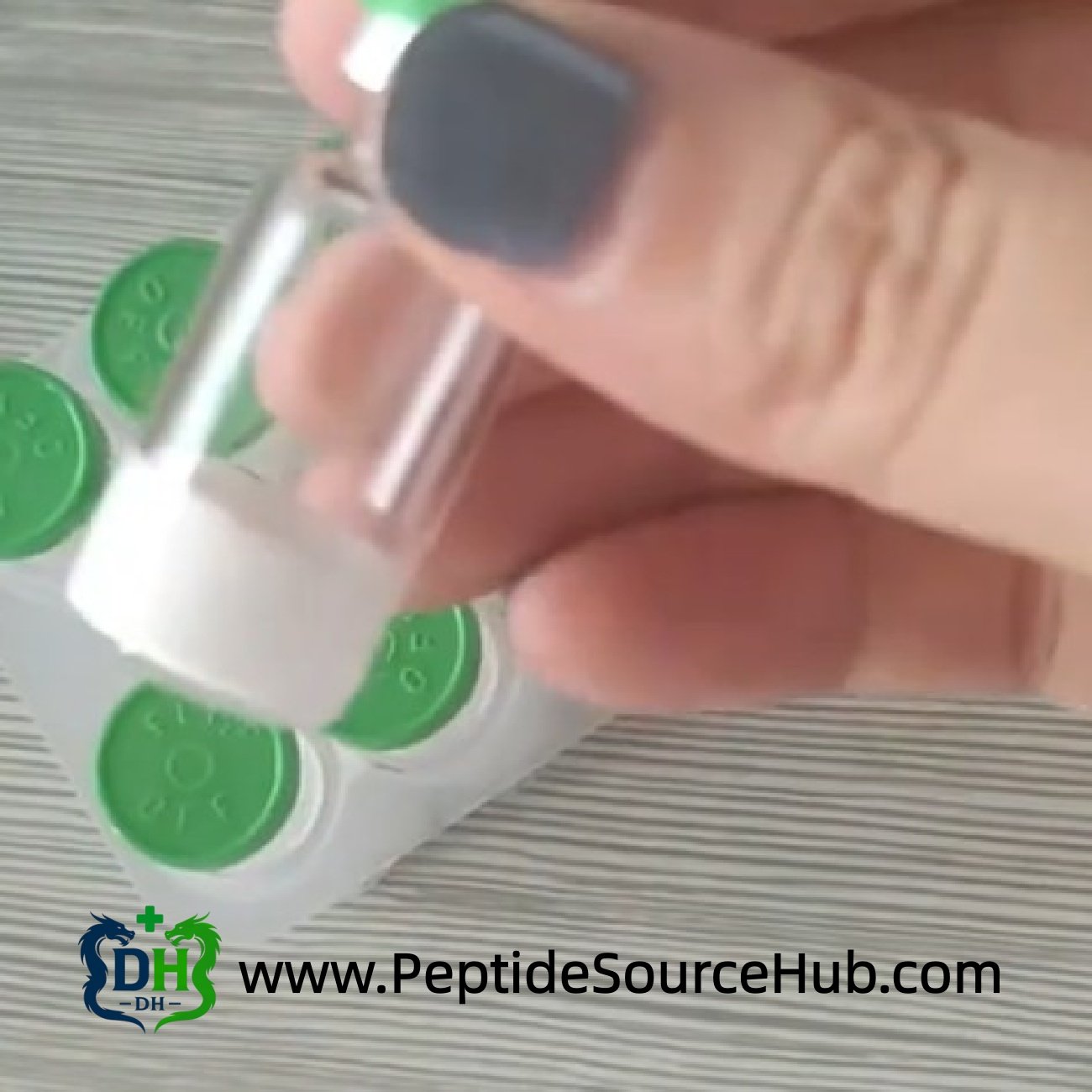 Hand holding single green cap Triptorelin vial over tray